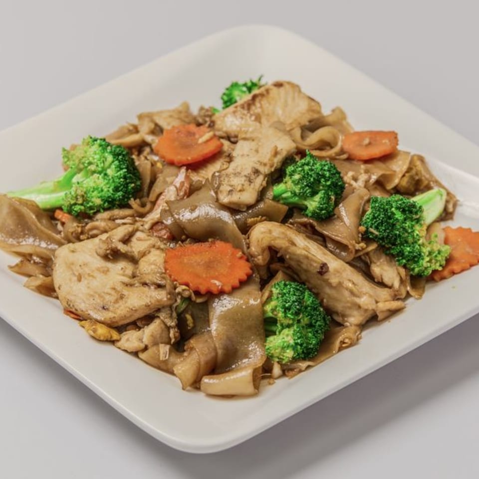 Sisters Asian Eatery's Thai dish with wide noodles, chicken, broccoli, and sliced carrots on a white plate.