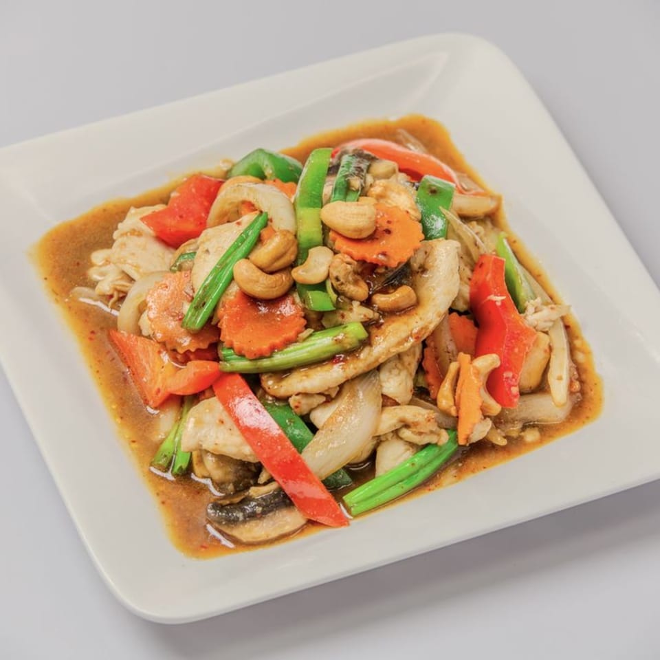 Thai cashew chicken stir-fry with carrots, bell peppers, onions, and green beans in a savory sauce.